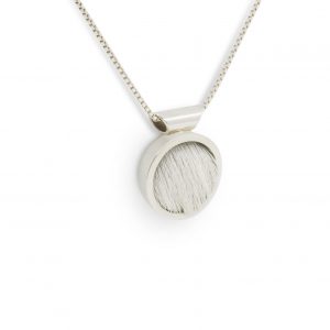 Colgante de plata 925 y piel de vacuno blanca, diámetro 15mm, grosor 4mm. Cadena de plata 925 tipo veneciana, longittud opcional 40cm, 45cm o 50cm. Objeto diseñado y fabricado artesanalmente en Madrid, España, por el estudio-taller de malicia. Este colgante ha sido fabricado por personas que disfrutan su trabajo