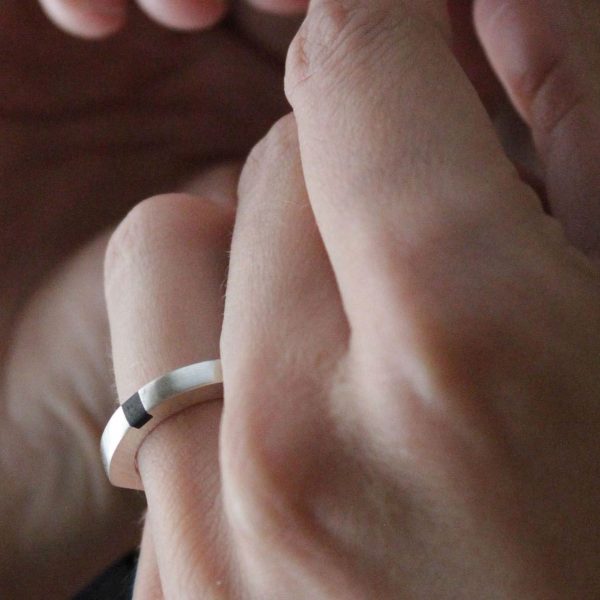 Anillo macizo de plata 925 mate con incrustación de madera de ébano. Anchura 4mm. Interior pulido. Los rebajes laterales lo convierten en un anillo particularmente cómodo, y mantienen la incrustación de ébano en el revés de la mano. Objeto diseñado y fabricado artesanalmente en Madrid, España, por el estudio-taller de malicia. Este anillo ha sido fabricado por personas que disfrutan su trabajo.