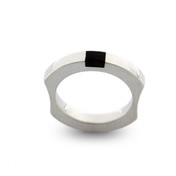 Anillo macizo de plata 925 mate con incrustación de madera de ébano. Anchura 4mm. Interior pulido. Los rebajes laterales lo convierten en un anillo particularmente cómodo, y mantienen la incrustación de ébano en el revés de la mano.