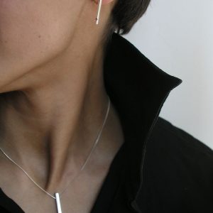 Colgante de plata 925 mate de 25mm de longitud, con rubí talla brillante de 2mm.  Cadena de plata 925, longitud opcional 40, 45 o 50cm. Cierre de "reasa" pequeña. Objeto diseñado y fabricado artesanalmente en Madrid, España, por el estudio-taller de malicia. Este anillo ha sido fabricado por personas que disfrutan su trabajo.