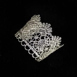 Pieza única diseñada y fabricada artesanalmente por el estudio-taller de malicia. Plata 925 envejecida. Objeto fabricado por personas que disfrutan su trabajo. En 2016, con motivo 400 aniversario del fallecimiento de Miguel de Cervantes y Saavedra, el estudio-taller edita una serie de piezas de joyería inspiradas en la figura del literato, la estética de su tiempo, y su obra más universal, El Quijote. Esta pieza construida íntegramente con plata 925, recrea aquellas puñetas bordadas que asomaban bajo las mangas del sobrio atuendo negro del típico hidalgo español del Renacimiento y Barroco. Esta estética en el vestir fue inmortalizada por el Greco en su “caballero de la mano en el pecho”, otrora considerado erróneamente un retrato de Cervantes.