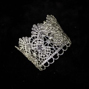 Pieza única diseñada y fabricada artesanalmente por el estudio-taller de malicia. Plata 925 envejecida. Objeto fabricado por personas que disfrutan su trabajo. En 2016, con motivo 400 aniversario del fallecimiento de Miguel de Cervantes y Saavedra, el estudio-taller edita una serie de piezas de joyería inspiradas en la figura del literato, la estética de su tiempo, y su obra más universal, El Quijote. Esta pieza construida íntegramente con plata 925, recrea aquellas puñetas bordadas que asomaban bajo las mangas del sobrio atuendo negro del típico hidalgo español del Renacimiento y Barroco. Esta estética en el vestir fue inmortalizada por el Greco en su “caballero de la mano en el pecho”, otrora considerado erróneamente un retrato de Cervantes.