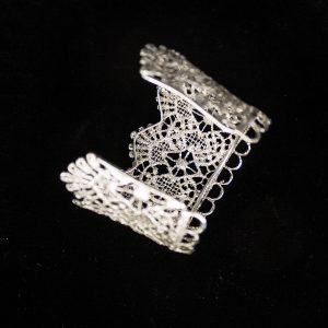 Pieza única diseñada y fabricada artesanalmente por el estudio-taller de malicia. Plata 925 envejecida. Objeto fabricado por personas que disfrutan su trabajo. En 2016, con motivo 400 aniversario del fallecimiento de Miguel de Cervantes y Saavedra, el estudio-taller edita una serie de piezas de joyería inspiradas en la figura del literato, la estética de su tiempo, y su obra más universal, El Quijote. Esta pieza construida íntegramente con plata 925, recrea aquellas puñetas bordadas que asomaban bajo las mangas del sobrio atuendo negro del típico hidalgo español del Renacimiento y Barroco. Esta estética en el vestir fue inmortalizada por el Greco en su “caballero de la mano en el pecho”, otrora considerado erróneamente un retrato de Cervantes.
