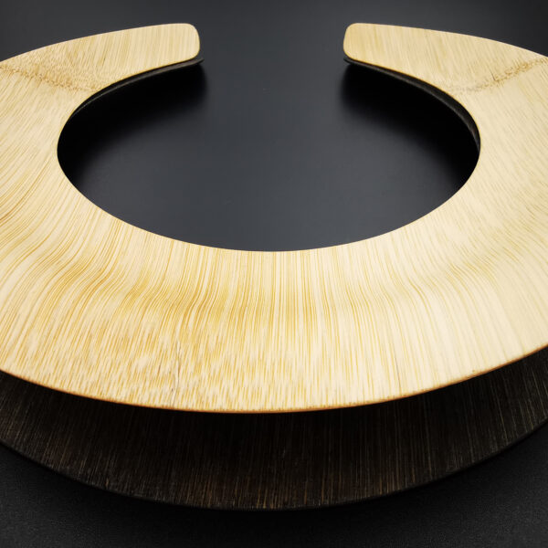 Gargantilla doble al estilo de los collares masai. Bambú laminado, acabado encerado (cera de abeja), una de ellas tintada. Flexible y ligero. Medidas (aproximadas): diámetro interior 14cm, exterior 23cm. Objeto diseñado y fabricado en Madrid por personas que disfrutan de su trabajo.