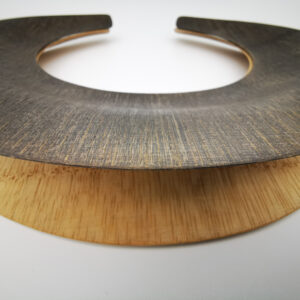 Gargantilla doble al estilo de los collares masai. Bambú laminado, acabado encerado (cera de abeja), una de ellas tintada. Flexible y ligero. Medidas (aproximadas): diámetro interior 14cm, exterior 23cm. Objeto diseñado y fabricado en Madrid por personas que disfrutan de su trabajo.
