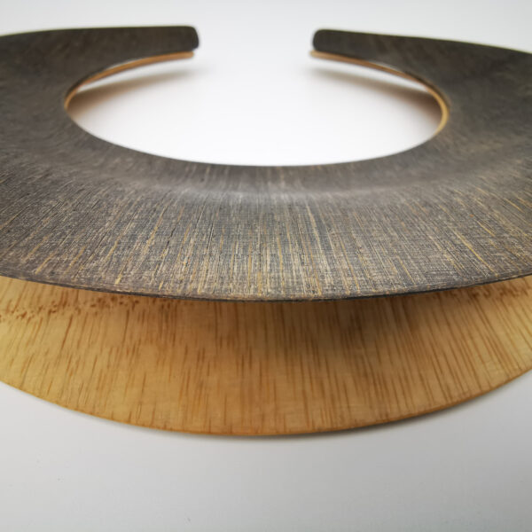 Gargantilla doble al estilo de los collares masai. Bambú laminado, acabado encerado (cera de abeja), una de ellas tintada. Flexible y ligero. Medidas (aproximadas): diámetro interior 14cm, exterior 23cm. Objeto diseñado y fabricado en Madrid por personas que disfrutan de su trabajo.