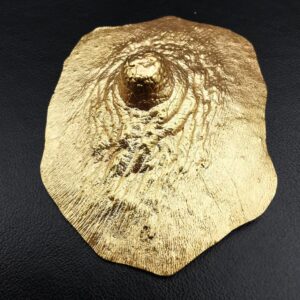 Pezón dorado, broche. Bronce con baño de oro de 18kt. Medidas aprox. 5x3,7cm, Peso 13g.